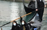 Des tpiristes asiatiques portent des masques de protection lors d'un tour en gondole à Venise, le 24 février 2020. 