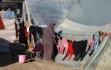 Une femme étend des vêtements dans un camp de Palestiniens déplacés à Rafah, dans le sud de la bande de Gaza, le 16 décembre 2023