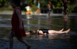 Des enfants se rafraichissent dans l'eau d'un bassin à Nantes, le 18 juillet 2022, alors que la température dépasse les 42 degrés Celsius
