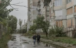 Des habitants marchent près d'un immeuble d'habitation endommagé par des attaques aériennes, le 30 octobre 2026 à Kherson, dans le sud de l'Ukraine 
