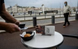 Un homme portant un masque de protection passe à côté de la terrasse d'un café sur le Vieux Port, le 2 juin 2020 à Marseille