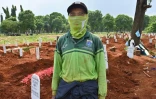 Le fossoyeur Junaidi Hakim devant des tombes de personnes décédées du coronavirus au cimetière de Pondok Ranggon, le 6 mai 2020 à Jakarta, en Indonésie