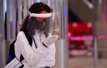 Une touriste consulte son téléphone en attendant un test de température à l'aéroport de Dubaï, le 8 juillet 2020