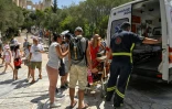 Une touriste âgée est prise en charge par un ambulancier après s'être évanouie pendant la visite de l'Acropole, le 20 juillet 2023 à Athènes