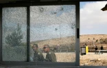 Des forces de sécurité israéliennes passent devant les vitres brisées du poste de contrôle de Har Adar, le 26 septembre 2017