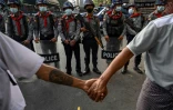 Des manifestants anti-junte forment une chaîne humaine devant les forces de l'ordre birmanes, le 15 février 2021 à Rangoun