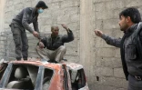 Des secourites aident un homme sur le site d'un bombardement du régime à Douma, ville du fief rebelle de la Ghouta orientale près de Damas, le 22 février 2018