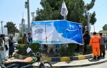 Des employés municipaux et des talibans installent des banderoles sur un rond-point, à la veille du troisimèe anniversaire de la prise de pouvoir par les talibans en Afghanistan, le 13 août 2024 à Kaboul