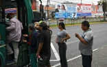 Des personnes montent dans un bus près d'affiches de campagne à Lima, le 11 avril 2026
