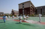 Des bénévoles désinfectent l'enceinte d'une école avant sa réouverture, le 12 avril 2020 à Weifang (Chine)