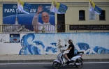 Une personne circule près d'une affiche posée pour la visite du pape Léon XIV, le 3 juillet 2026 à Lampedusa (Italie)