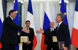 Patrick Pouyanné (g), PDG du groupe Total et le patron du groupe Novatek Leonid Mikhelson (g) se serrent la main après la signature d'un accord, en présence des présidents russe Vladimir Poutine (d) et français Emmanuel Macron, le 24 mai 2018 à Strelna, près de Saint-Pétersbourg