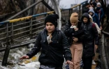 Un jeune évacué a une peluche placée sur le devant de sa veste alors qu'il traverse avec d'autres habitants un pont détruit pour quitter la ville d'Irpin, au nord-ouest de Kiev, le 7 mars 2022.