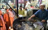 Un cuisinier fait griller des kebabs sous l'oeil de ses clients dans le quartier de Namak Mandi à Peshawar, le 13 décembre 2018