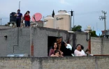 Des voisins écoutent de leur toit le DJ mexicain Roberto Garcia dans une banlieue de Mexico, le 18 juilet 2020
