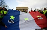 Des "gilets jaunes" brandissent un drapeau frappé d'étoiles et de trois dates : 1789, 1968, et 2018, à Paris, le 8 décembre 2018