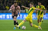 Le défenseur nantais Nicolas Cozza (C) tacle le Parisien Désiré Doué (g) lors du match nul (1-1) pour la 29e journée de Ligue 1, à Nantes le 22 avril 2025