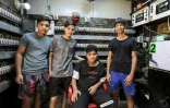 L'Irakien Karrar Ghaleem (assis), 17 ans, pose avec ses amis le 17 juillet 2021 dans l'entreprise de son père, un fournisseur privé de générateurs électriques dans le quartier de Sadr City à Bagdad, qui alimente plusieurs maisons lorsque le réseau national défaillant tombe en panne