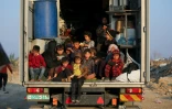 Des enfants palestiniens déplacés sont assis à l'arrière d'un camion alors que des personnes se déplacent du sud vers le nord de la bande de Gaza, dans le centre de Gaza, le 29 janvier 2025