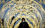 Un homme portant un masque médical pour se protéger contre le coronavirus marche parmi les décorations de Noël près de la Cathédrale du Christ-Sauveur dans le centre de Moscou, le 18 décembre 2020