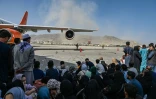 Des Afghans assis sur le tarmac de l'aéroport de Kaboul pris d'assaut dans l'espoir d'une évacuation après la reprise de la capitale par les talibans, le 16 août 2021 