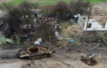 Epave d'un tank près de maisons détruites dans le village de Zalissya (Ukraine), au nord-est de Kiev, le 19 avril 2022
