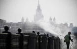 Un agent municipal désinfecte les bords des quais à Moscou, devant l'université d'Etat, le 28 mars 2020