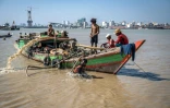 Des hommes récupèrent un navire coulé dans le fleuve Yangon, le 20 février 2024 à Rangoun, en Birmanie