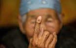 Une femme âgée montre la marque sur son doigt après avoir voté depuis son domicile avec une urne portable, le 27 juin 2024, un jour avant les élections législatives mongoles à Oulan-Bator, la capitale de la Mongolie.