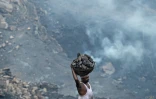 Un homme transporte du charbon d'une mine à ciel ouvert dans la périphérie de Dhanbad, le 6 juillet 2023 en Inde