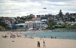 Un hélicoptère de la police patrouille au-dessus de la plage de Bondi le 22 décembre 2025 alors que la vie reprend progressivement après sept jours de deuil qui ont suivi l'attentat antisémite 