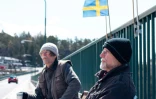 Pontus Berglund (g) et son frère jumeau Ola bavardent, l'un en Suède, l'autre en Norvège, sur le pont reliant les deux pays, le 1er mai 2021 à Svinesund