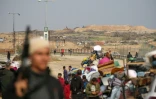 Déplacés palestiniens en route vers le nord de Gaza, surveillés par un char israélien, à Nousseirat, le 28 janvier 2025