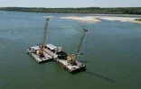 Deux dragueuses travaillent à approfondir le chenal navigable du Danube près du village de Cochirleni en Roumanie, le 12 août 2026