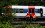 Des employés de la SNCF près d'un RER à l'arrêt après un déraillement entre Saint-Rémy-les-Chevreuse et Courcelle-sur-Yvette le 12 juin 2018