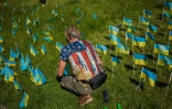 Un homme plante des drapeaux ukrainiens portant les noms des personnes tuées en raison de l'invasion russe, sur la place de l'Indépendance à Kiev le 3 juin 2022
