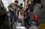 Des Palestiniens remplissent des contenants d'eau, le 17 mars 2024 à Rafah dans la bande de Gaza
