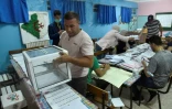 Des assesseurs comptent des bulletins de vote dans un bureau de vote en banlieue d'Alger, le 12 juin 2021