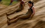 Des participants du "Mud day challenge" glissent dans la boue lors d'une des épreuves de la course d'obstacles, à Beyne, le 7 mai 2016