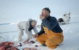 Les chasseurs inuits  Hjelmer Hammeken (G) et Martin Madsen (D) se partagent le foie d'un phoque annelé tout juste tué près d'Ittoqqortoormiit, le 28 avril 2024