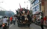 Des manifestants montés dans un camion de la police, portent le drapeau national du Népal devant la Maison du Président à Katmandou, le 9 septembre 2025