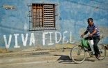Un Cubain passe à bicyclette devant un graffiti en hommage à Fidel Castro, le 
12 août 2014 à La Havane