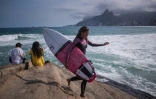 Une surfeuse s'apprĂŞte Ă s'adonner Ă son sport sur la plage d'Ipanema, Ă Rio de Janiero, le 30 juillet 2016