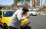 Un chauffeur de taxi se mouille le visage avec de l'eau pour se rafraîchir dans une rue de Téhéran, lors d'une vague de chaleur en Iran, le 22 juillet 2025