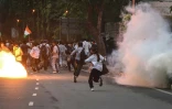 Des membres de la Rapid Action Force (RAF) tirent des grenades lacrymogènes pour disperser des partisans du "Parti du peuple des cafards" (CJP) lors d'une manifestation réclamant la démission du ministre de l'Éducation, en raison de fraudes présumées aux examens universitaires, le 20 juillet 2026 à New Delhi, en Inde