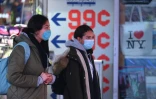 Deux femmes portant un masque contre le coronavirus traversent Times Square, le 12 mars 2020