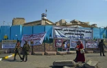 Des Irakiens marchent devant le conseil provincial de Diwaniya, en Irak, sur lequel est accrochée une bannière proclamant: "les conseils provinciaux ont été fermés sur ordre du peuple", le 3 novembre 2019