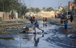 Des Palestiniens traversent une rue inondée à Deir el-Balah, dans le centre de la bande de Gaza, le 23 juillet 2024