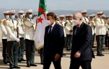 Le président français Emmanuel Macron (g), accueilli par son homologue algérien Abdelmadjid Tebboune, passent en revue la garde d'honneur à l'aéroport d'Alger, le 25 août 2022