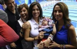 La mère de Michael Phelps Déborah (2è g) et sa compagne Nicole Johnson (c) avec son fils Boomer, sourient lors de la cérémonie de remise des médailles à l'issue du 4x100 m à Rio, le 13 août 2016  